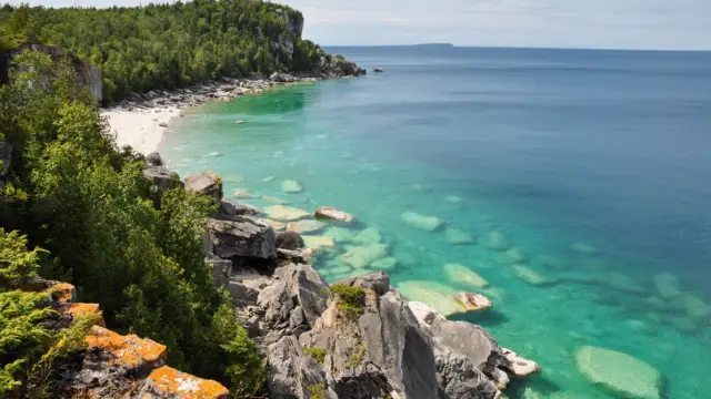 eaux cristallines bordée d'une plage et de rochers 